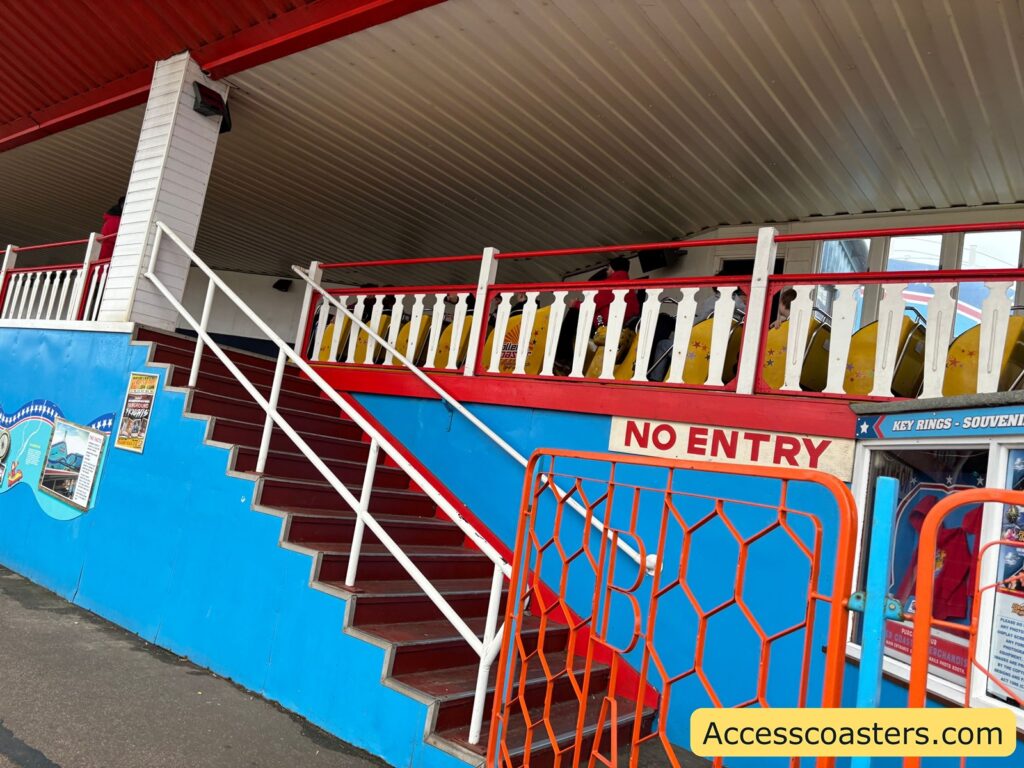 Stairway and “NO ENTRY” gate beside the Roller Coaster station, painted in blue and red.
