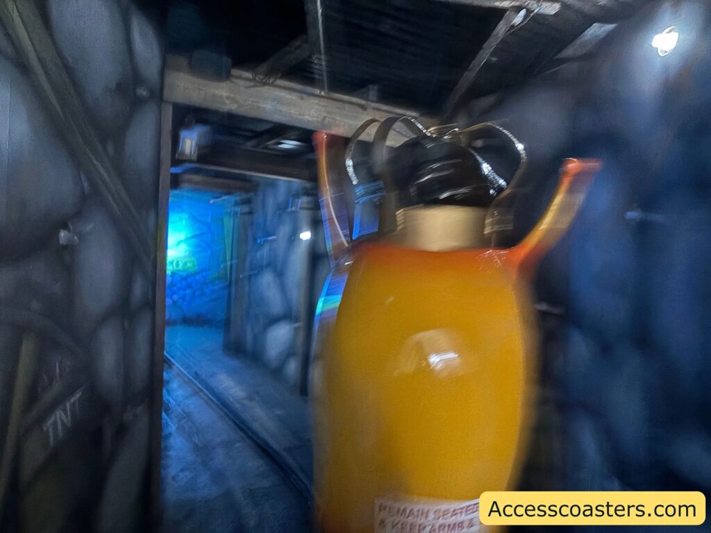  View from inside the ride with a bright yellow snail car entering a darkly lit, glowing section of the attraction.