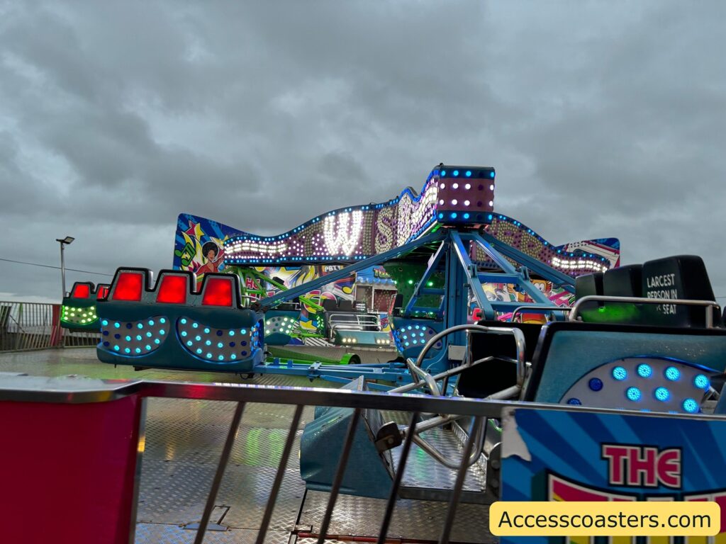 Wide shot of the Twister fairground ride with several brightly lit spinning cars