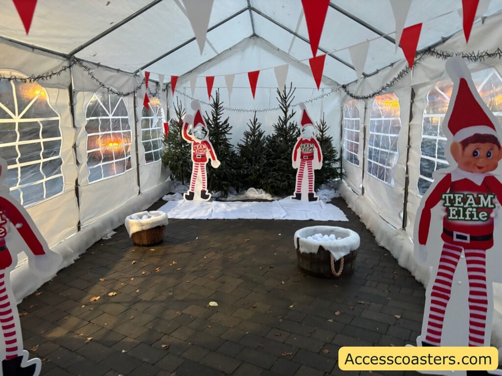 Inside a white tent with elf decorations, stripes, and snow-like setting. Multiple elf figures and snow ball for the snow ball fight 