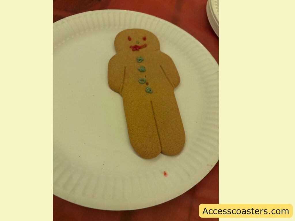 A close-up of a decorated gingerbread man on a white paper plate, with colorful icing details.