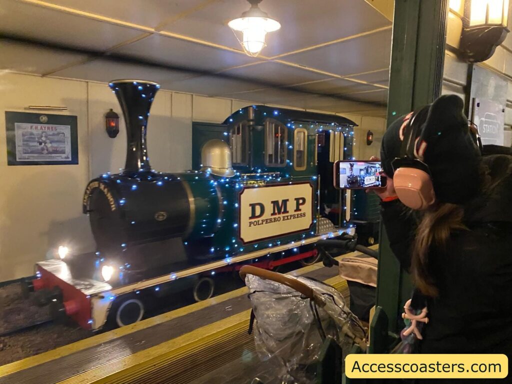 Blue model train labeled "DMP" at the station platform, with passengers boarding