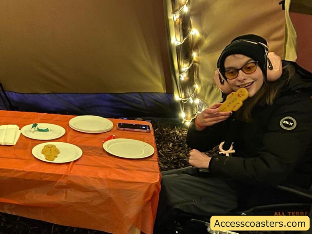 Iona Smiling  sitting at a table and happily eating a decorated gingerbread man.