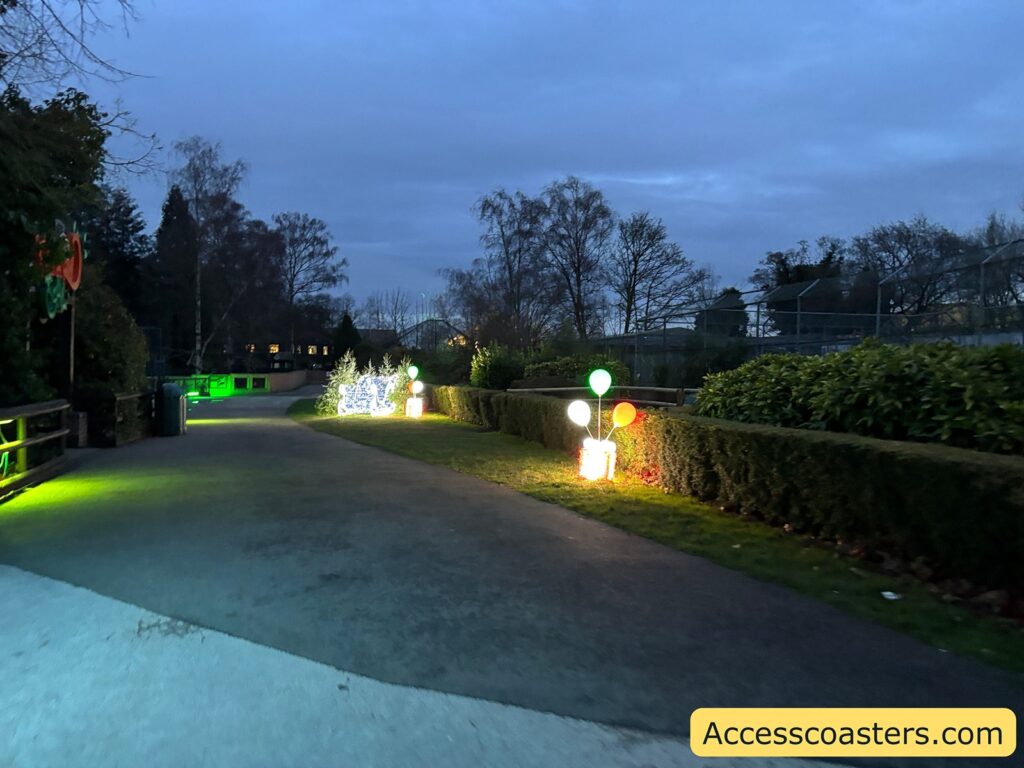 A pathway at dusk, gently illuminated by glowing green and yellow lights along the edges.
