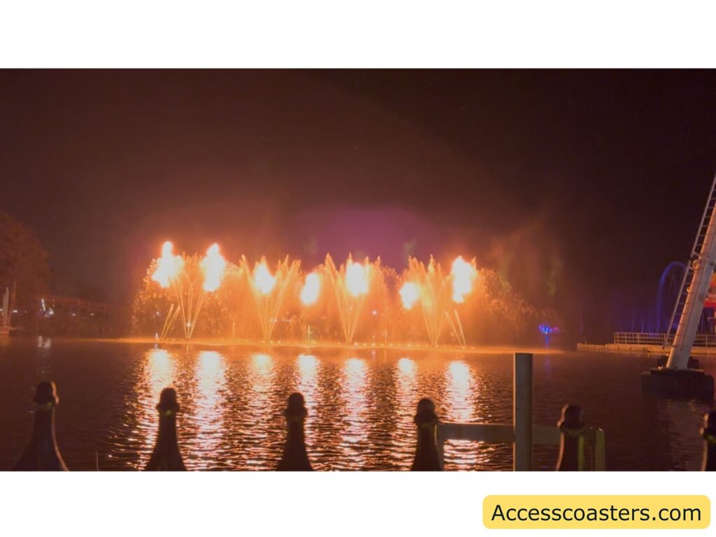 Lake stage with bright flames shooting upwards on the water during a nighttime show.