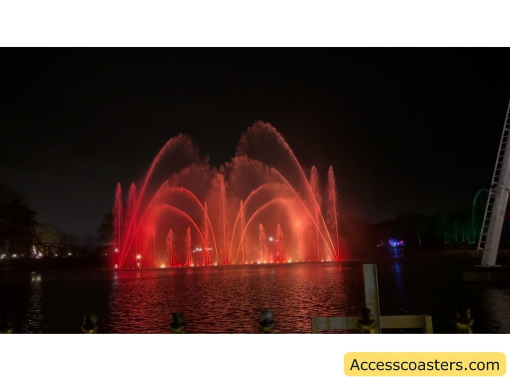 Multiple water fountains with changing colors illuminated against the night sky.