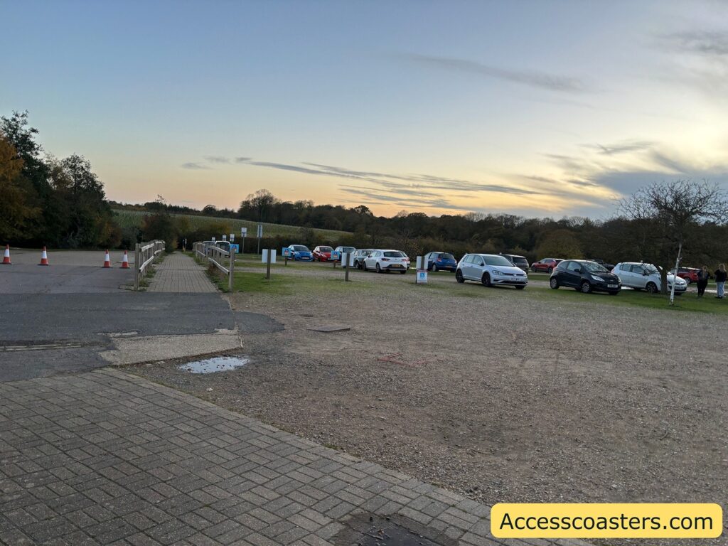 View of a car park cars parked on a mostly unpaved and uneven surface