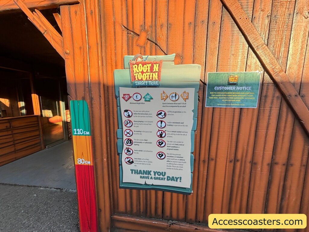 A close-up of the Root N Tootin Target Trail entrance sign and ride information board 