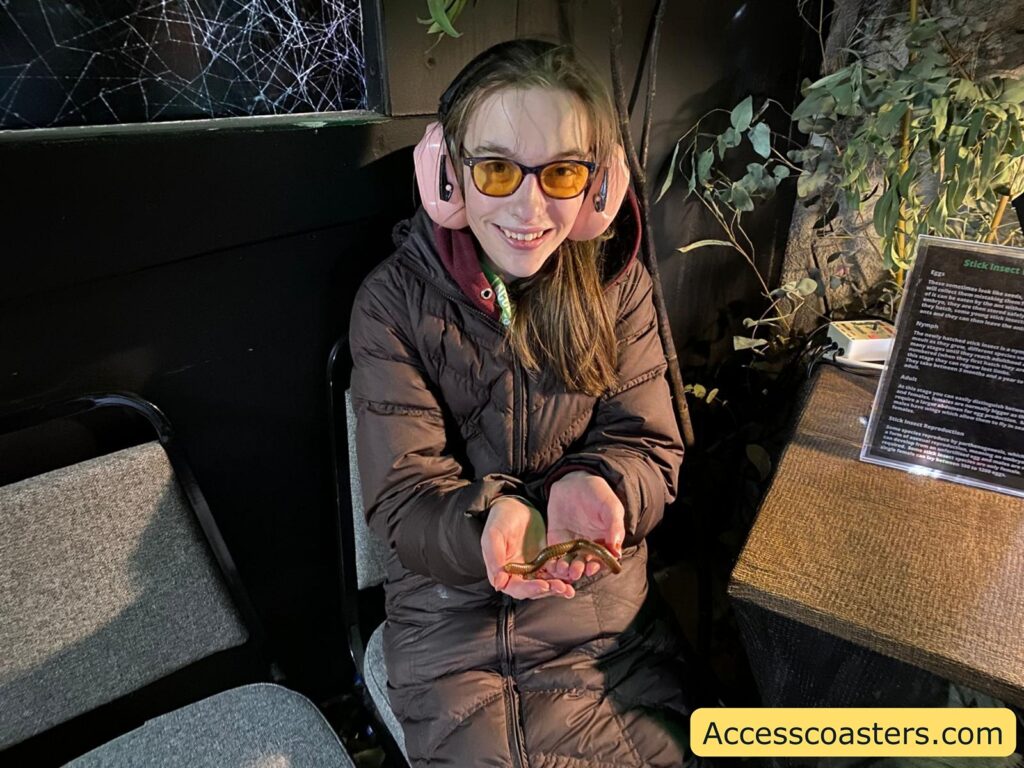 Iona  smiling and holding a centipede in the Creepy Cave handling area.