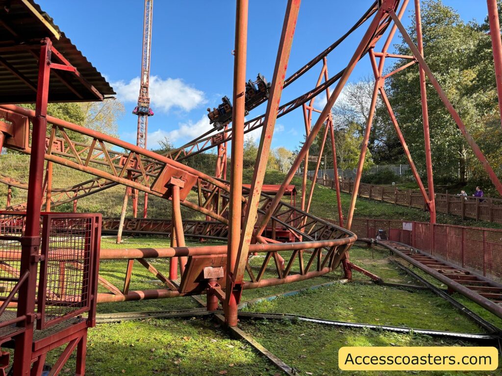 View of the Cannonball Express coaster track curving past a fence, with trees in the background.