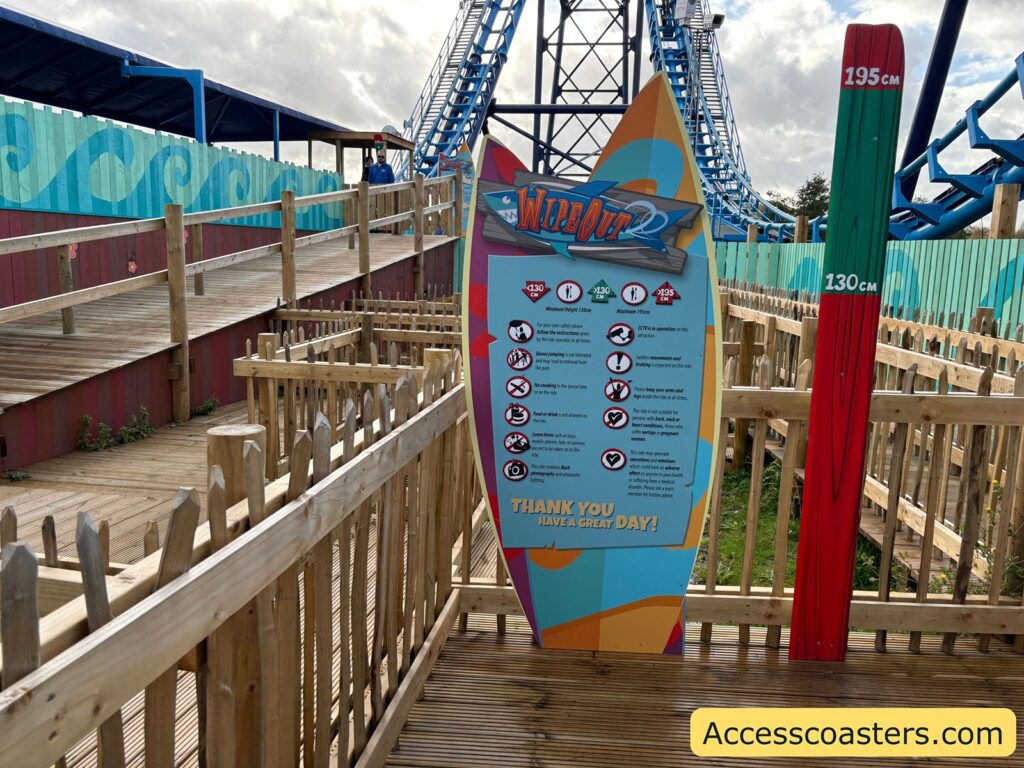 A colorful surfboard-shaped sign with "Wipeout" ride ristrictions and ride information on the sign

