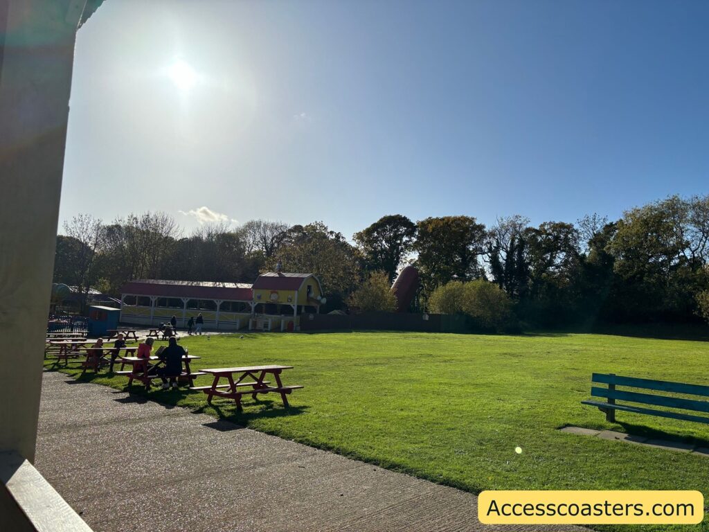 Picnic benches on a spacious grassy area in a theme park 