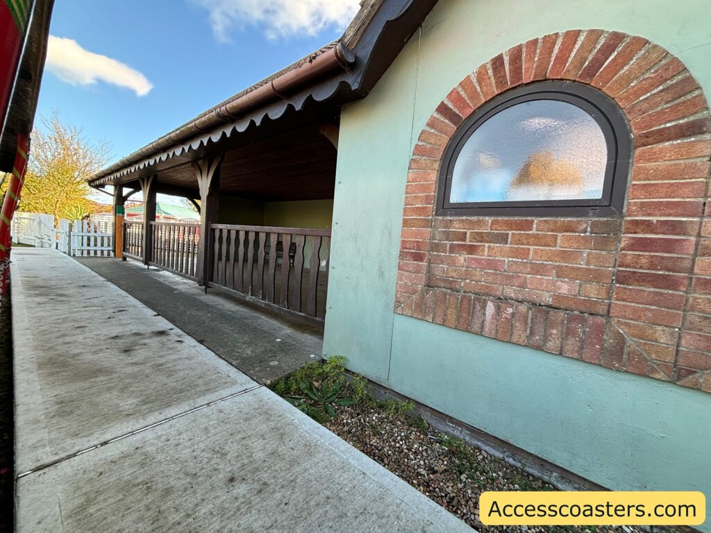 Paved pathway alongside a station building with an arched window.