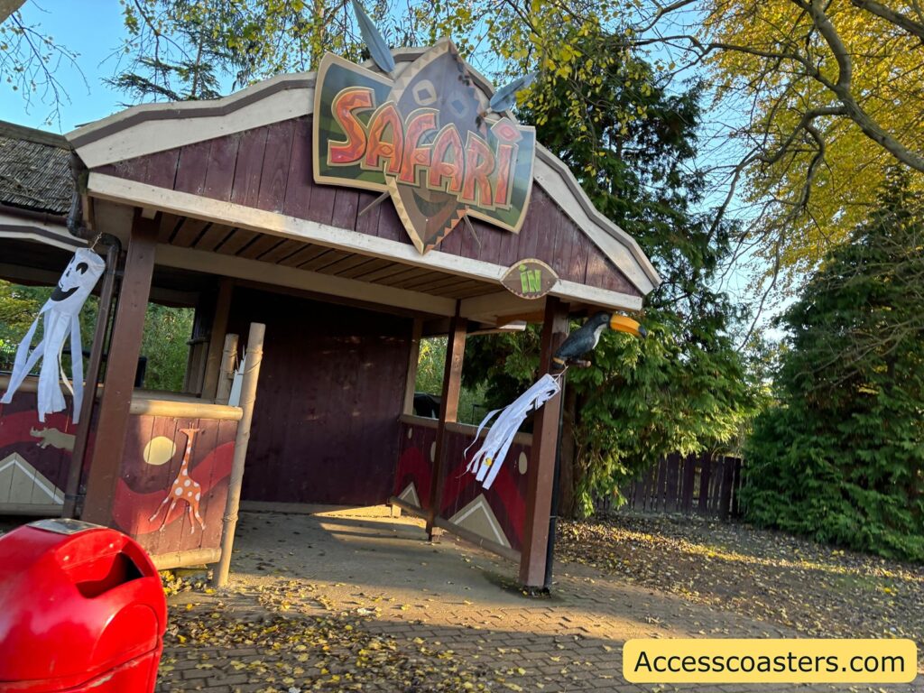 Entrance to the Safari ride, showing a small building decorated with safari-themed signs and surrounded by trees.