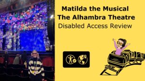 Iona stood infroant of the matida the musical stage with text that reads Matilda the Musical The Alhambra Theatre disabled access review. There is also a carotoon image of Iona riding a rollercoaster in the bottem corner and the visitor attraction symbol.