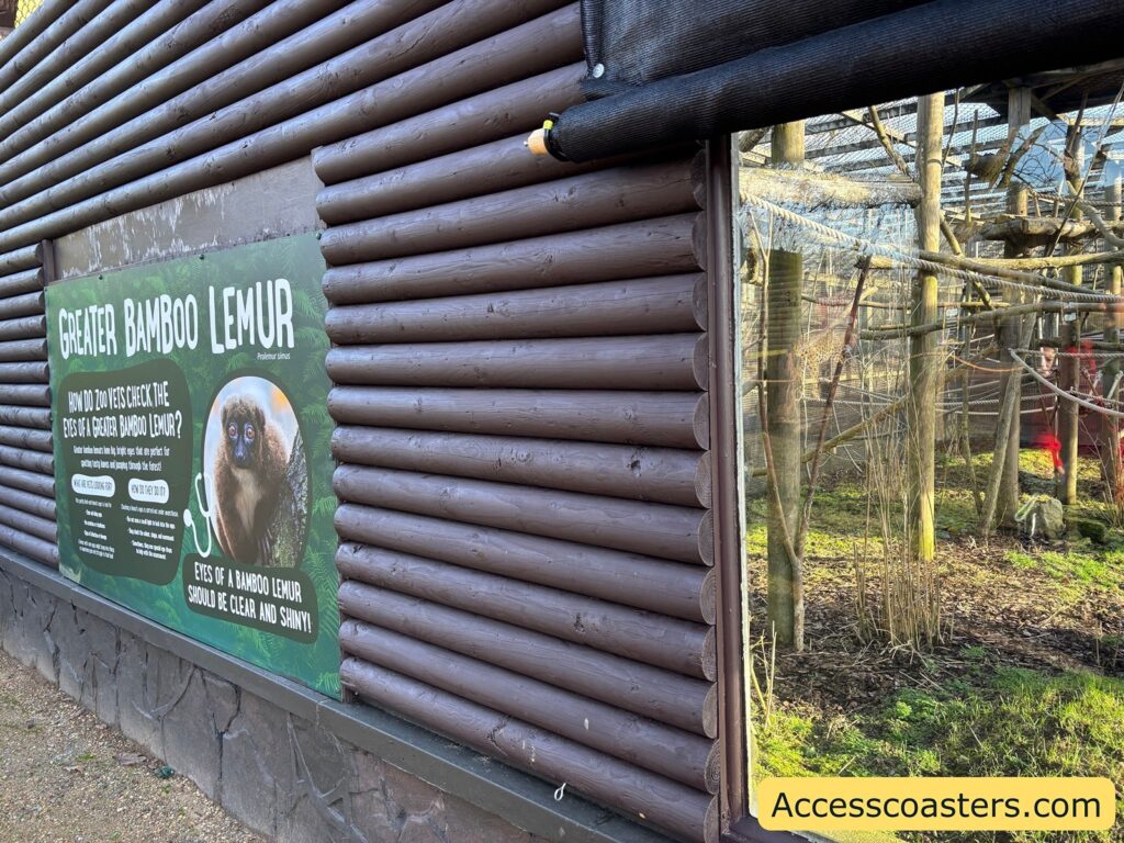 Close-up of a wooden zoo building wall with an animal-area information sign.
