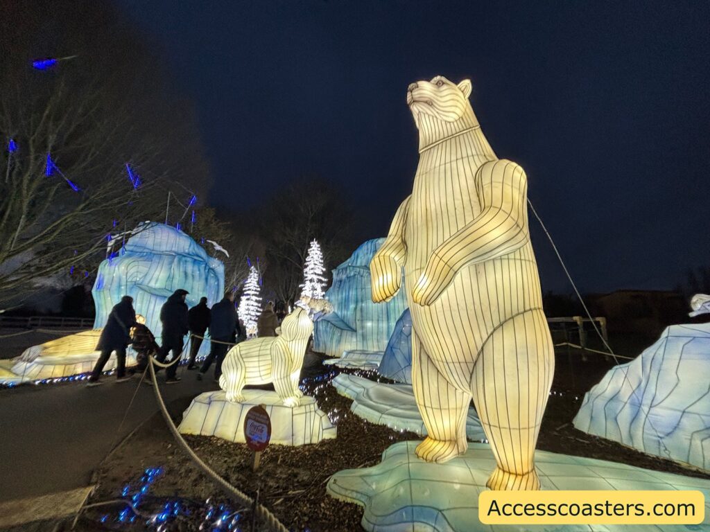 Night-time light trail display featuring a tall illuminated polar bear lantern sculpture, with glowing ice-shaped lights and an igloo-style tunnel nearby.
