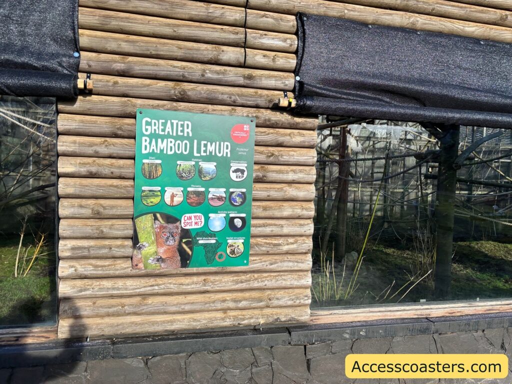 Close-up of a green “Meerkats and Lemurs” sign on a log-style wooden wall.
