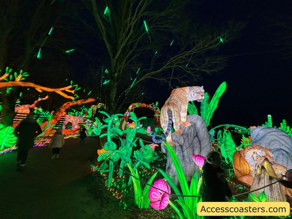 Glowing Amazon jungle display at night with dense neon plants and a spotted big-cat figure beside the trail.