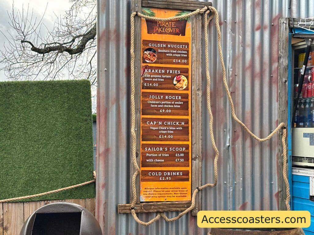 Close-up of the Chip Wrecked menu board framed with rope on corrugated metal, listing pirate-themed items such as Kraken Fries, Jolly Roger, Cap’n Chick’n, Sailor’s Scod, and cold drinks.