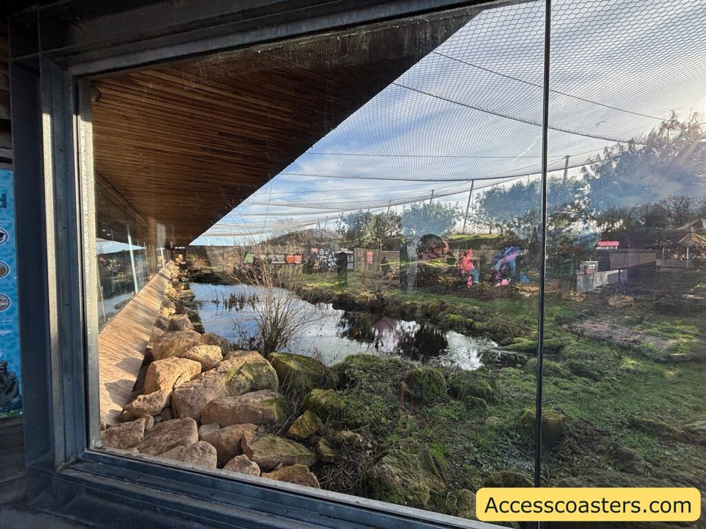 Window into snow lepord enclosure with lake and grass areas 