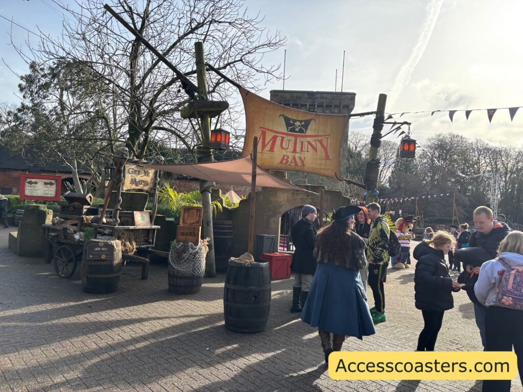 A small crowd gathered in front of a pirate-themed setup with a banner overhead and bunting strung across.
