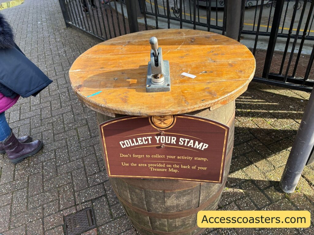 wooden barrel stamp station outdoors, with the metal stamp on top and a “COLLECT YOUR STAMP” sign on the front.