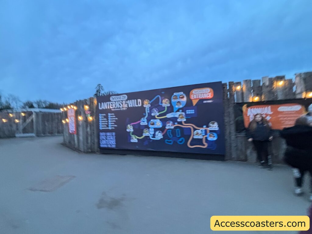 Outdoor approach at dusk with illuminated event signage and visitors walking toward the light trail entrance area.
