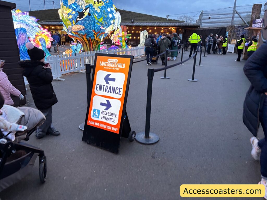 Queueing area with barriers and a “Lanterns Wild Entrance” sign pointing left as staff manage entry and ticket checks.