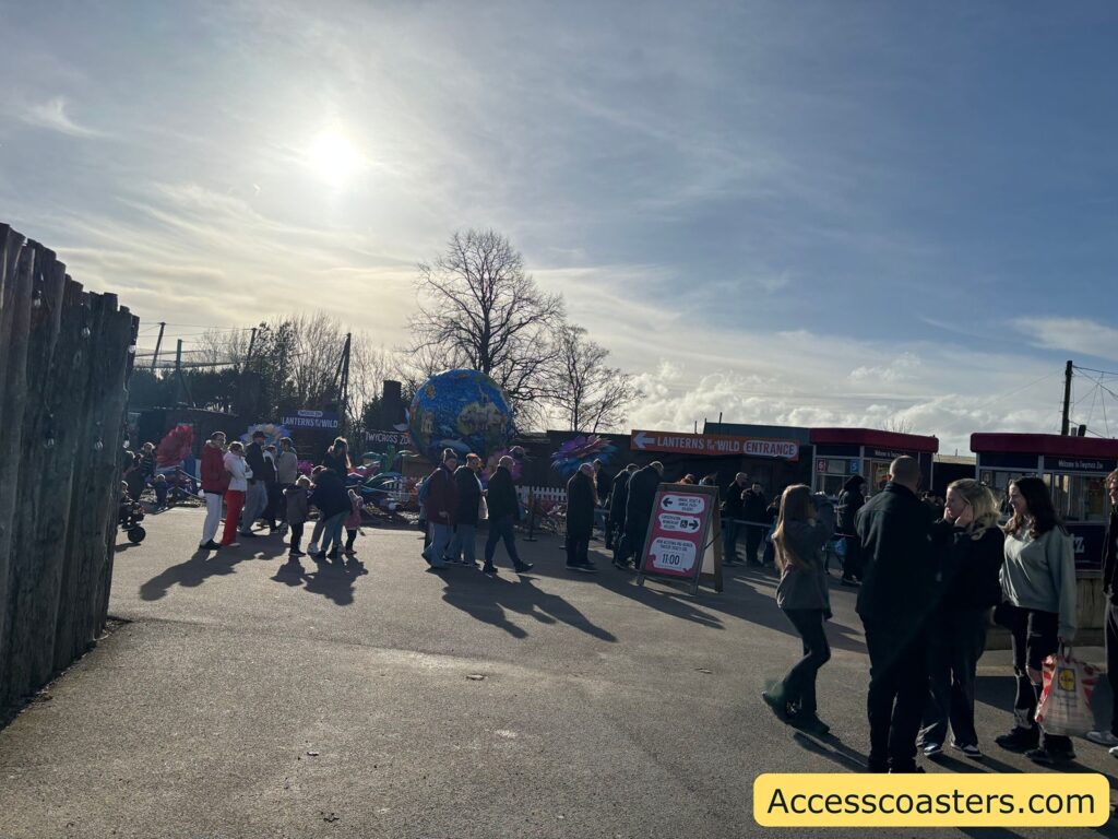 Busy entrance plaza with crowds queuing and walking toward the entry booths.
