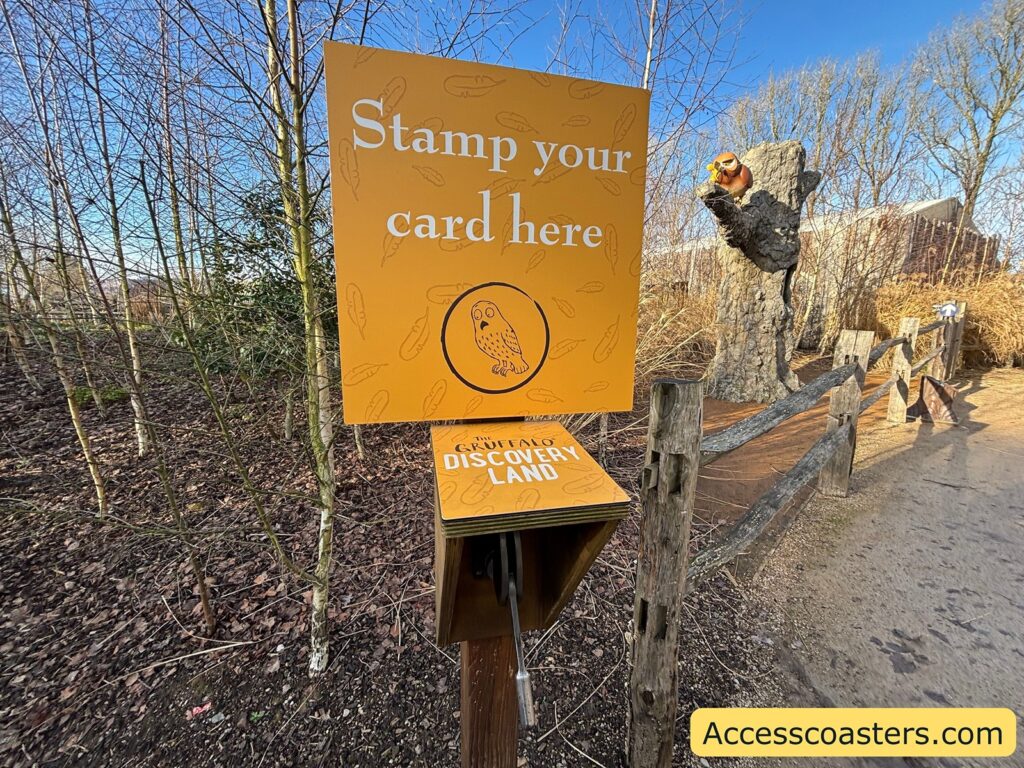 Orange sign reading “Stamp your card here” next to a stamp station on the Gruffalo trail.
