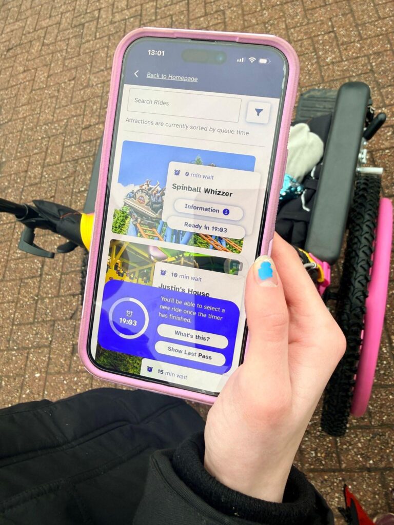The Ride Access Pass app is open on a map view, showing nearby attractions with an information pop-up of a countdown to next ride over the map.