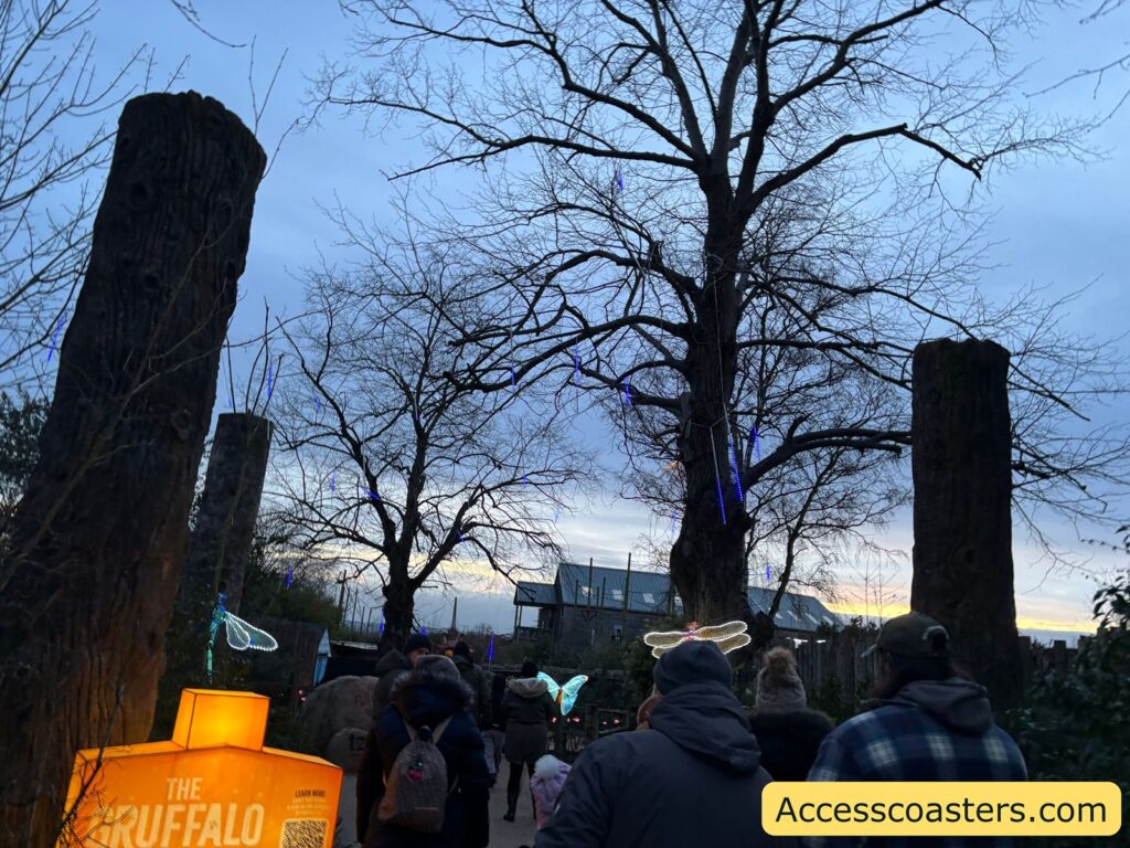 Crowded entrance area at dusk for the Gruffalo trail, with tall wooden posts and bare trees.
