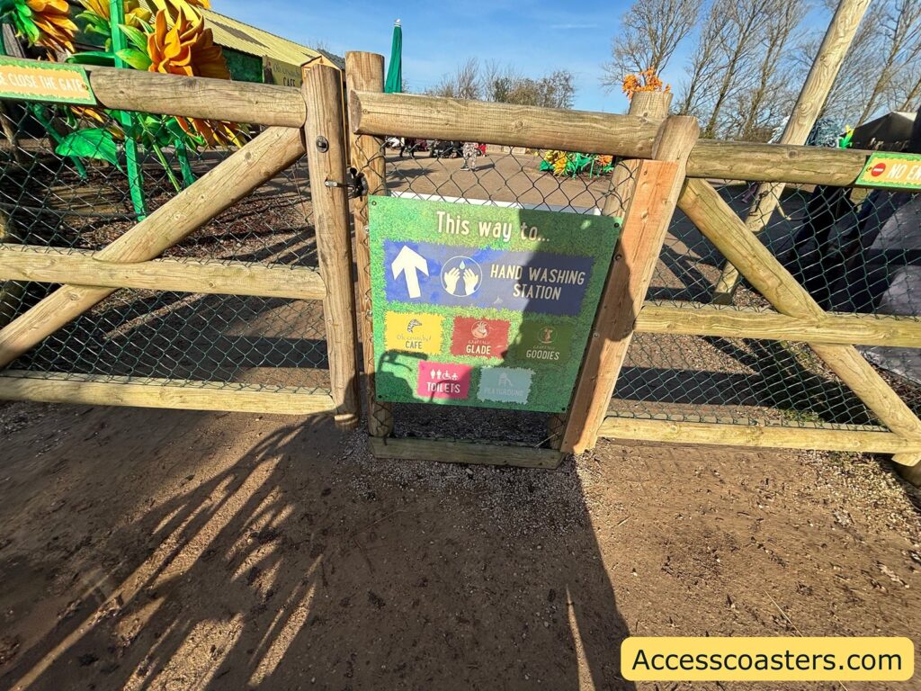 Wooden gate with wire mesh and a green “This way” directional sign pointing toward the goat walkthrough area.
