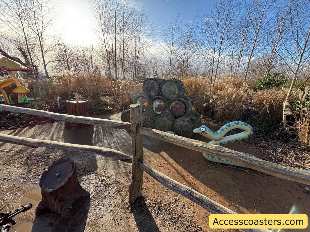 Path-side view of the Snake section with rope fencing and wooden posts, showing the themed logpile feature beside the trail.
