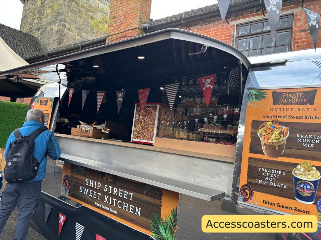 Side view of the courtyard bar counter with people ordering, with bunting and signage around the serving window.