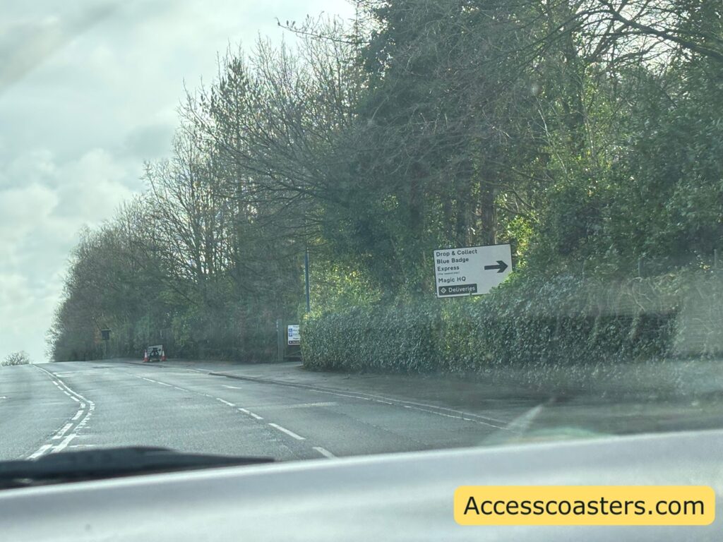 image of alton towers entrance road with sign that says drop and colection, blue badge and express parking with an arrow pointing to the turining.