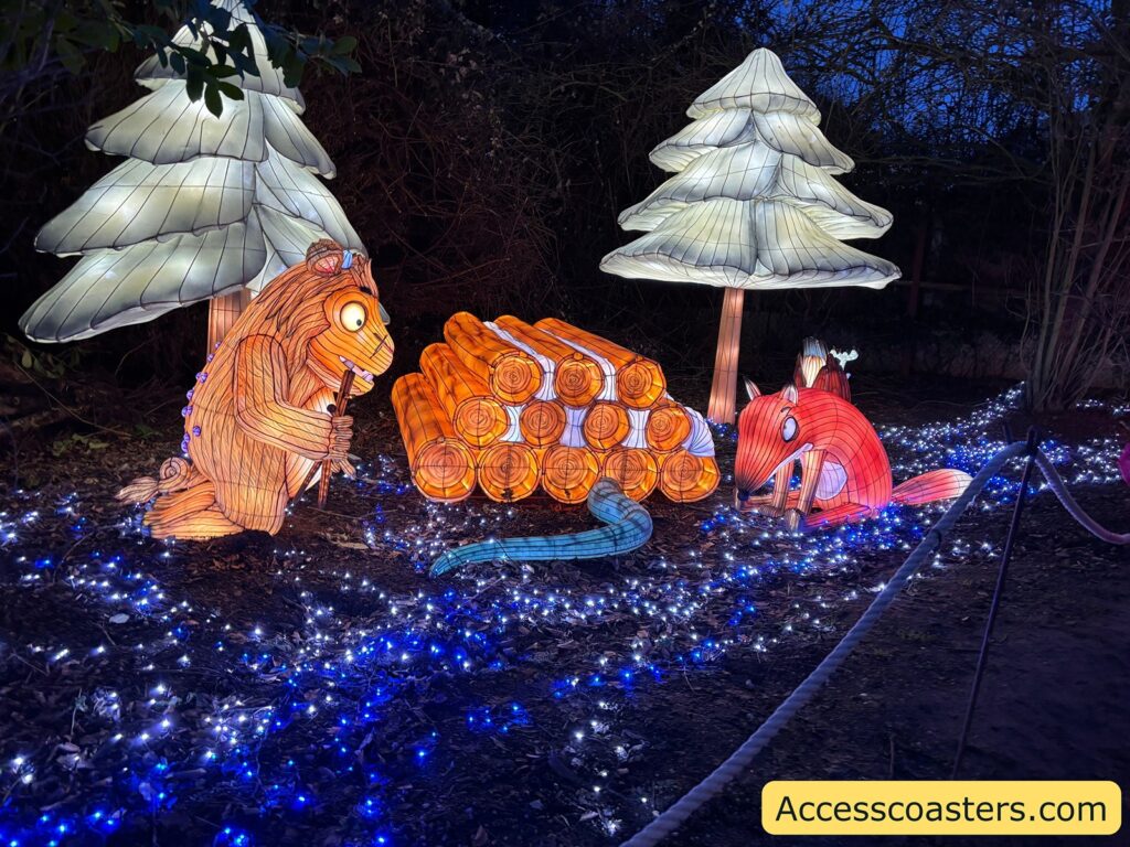 Illuminated woodland display featuring  Gruffalo character figures among glowing blue ground lights.
