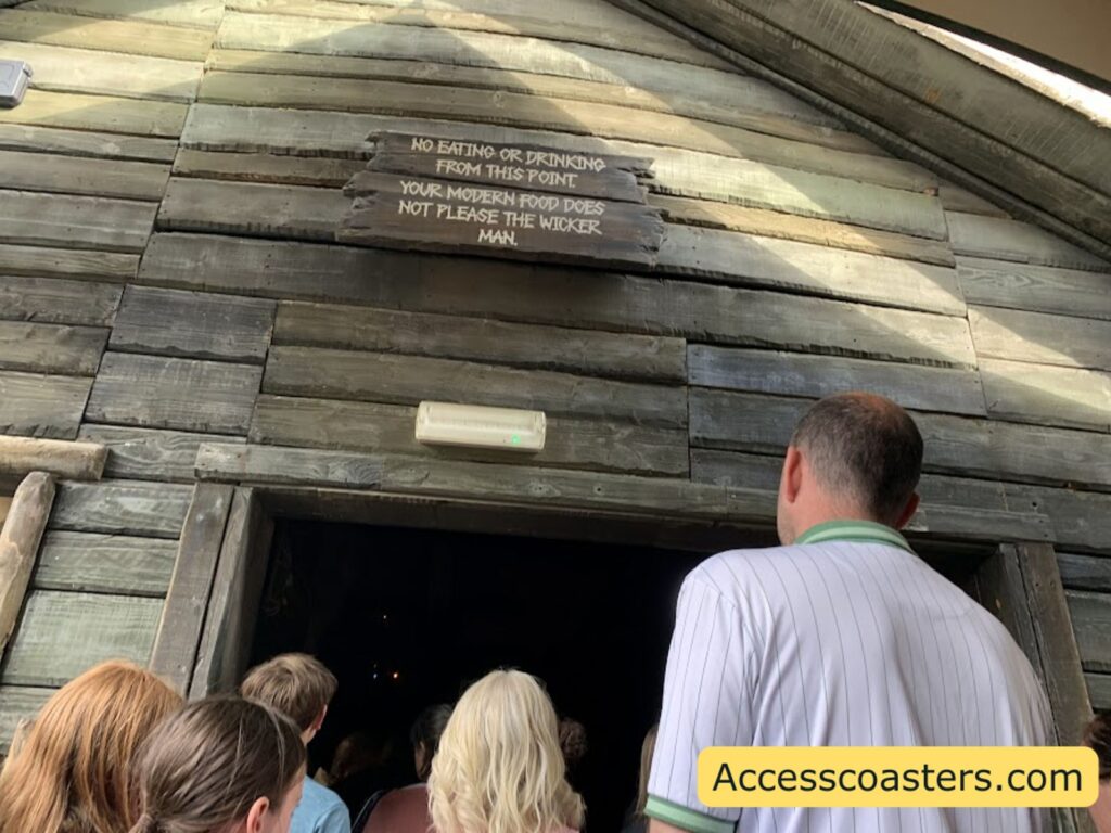Entrance to a wooden dark room where bag drop off and wait for pre show with people entering
