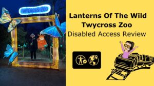 Featured image for blog post “Lanterns of the Wild” at Twycross Zoo: Iona standing inside a large illuminated picture-frame display surrounded by glowing blue butterflies, with the text “Disabled Access Review” on a yellow background.