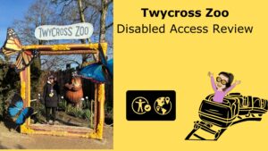 Featured image for “Twycross Zoo Disabled Access Review,” showing a split layout: on the left, Iona stands under the Twycross Zoo entrance arch decorated with large butterflies; on the right, a yellow panel displays the title with the symbol for visitor attractions and a cartoon person riding a track-based vehicle.