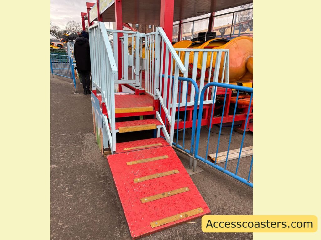The Speedy Coaster loading platform with red steps and a yellow-edged ramp that goes into stairs leading up to the station.