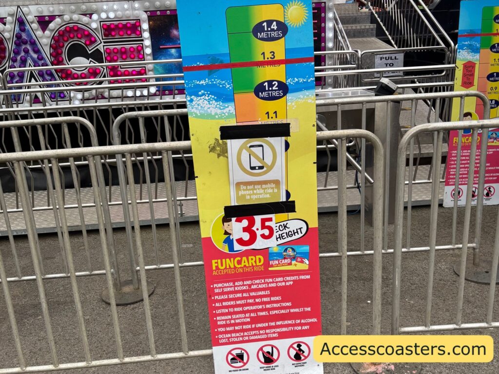 Close-up of the height‑measurement board and entry gate for the Space ride, showing a multicoloured height scale from 1.27 to 1.4 metres, a sign indicating the ride costs 3.5 credits using a Funcard, and safety icons and text rules