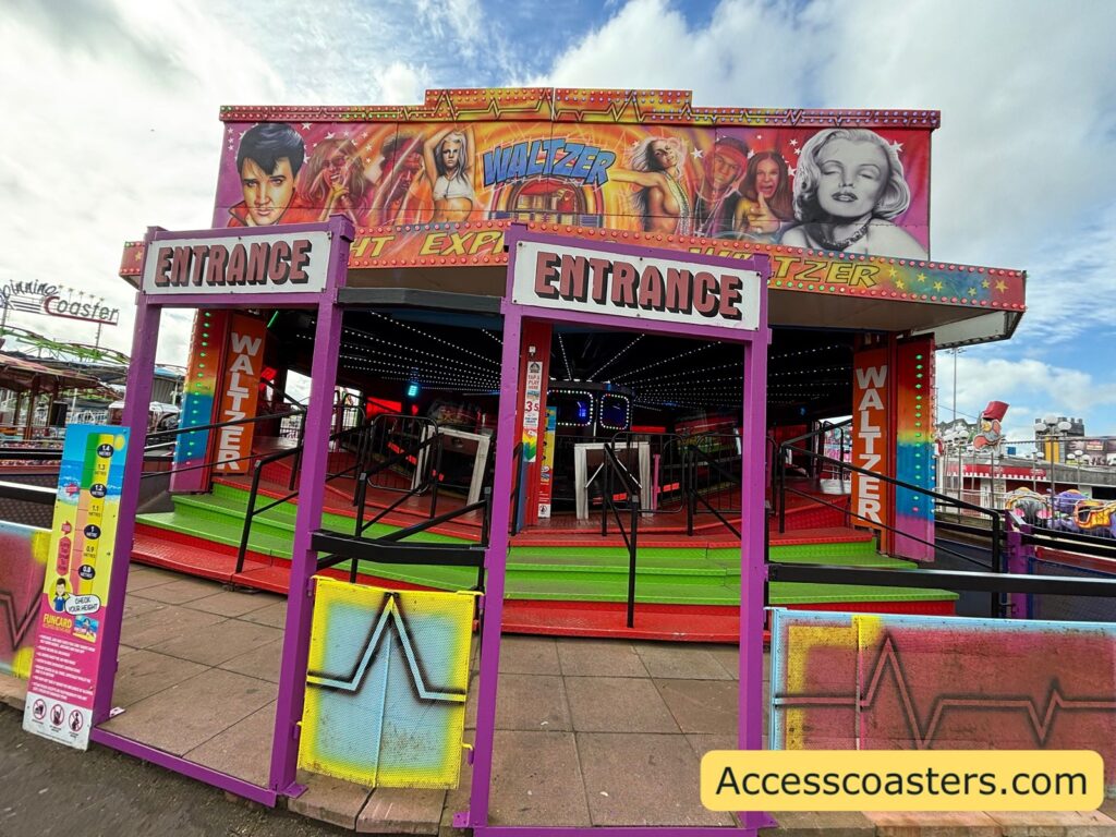 front view of colorful traditional fairground waltzer Two “ENTRANCE” signs are above the openings, and the ride’s circular platform with low railings and stairs 