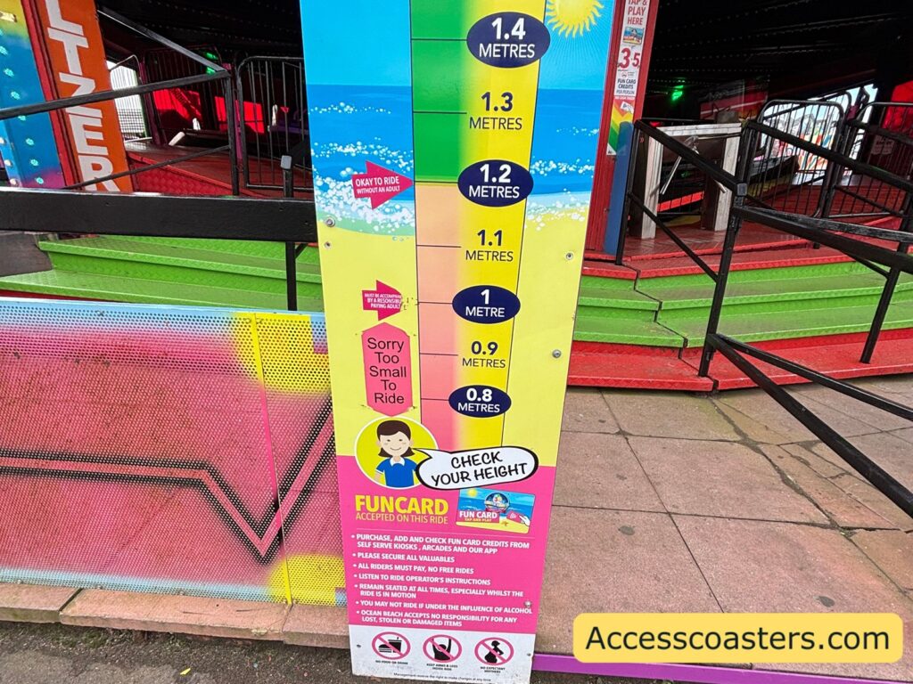 ride information board standing beside the waltzer platform, with multi‑colored sections listing height restrictions and rules