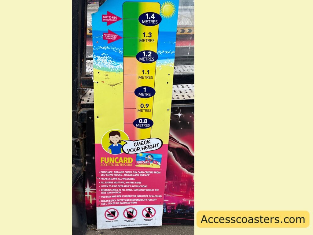 colourful height‑restriction sign for the Breakdance ride at Ocean Beach, showing minimum height requirements and small-print safety information at the bottom.
