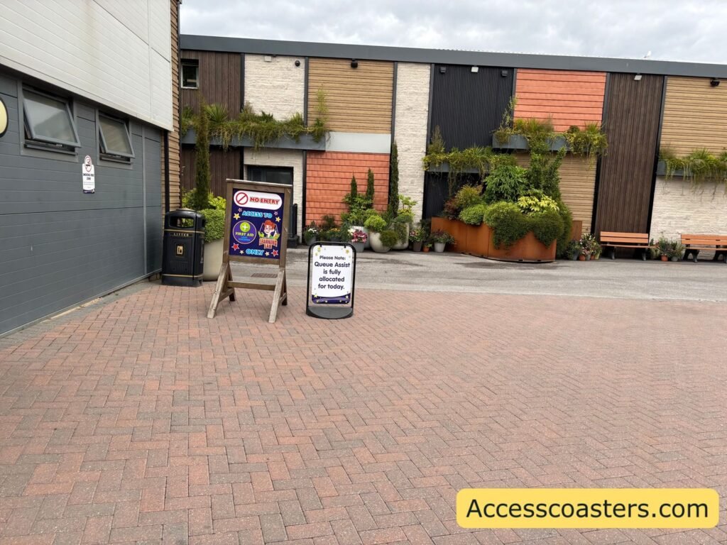 image of path leading to first aid with two sign one that reads access to first aid and learning lab only and the other sign reads queue assist is fully allocated for today 