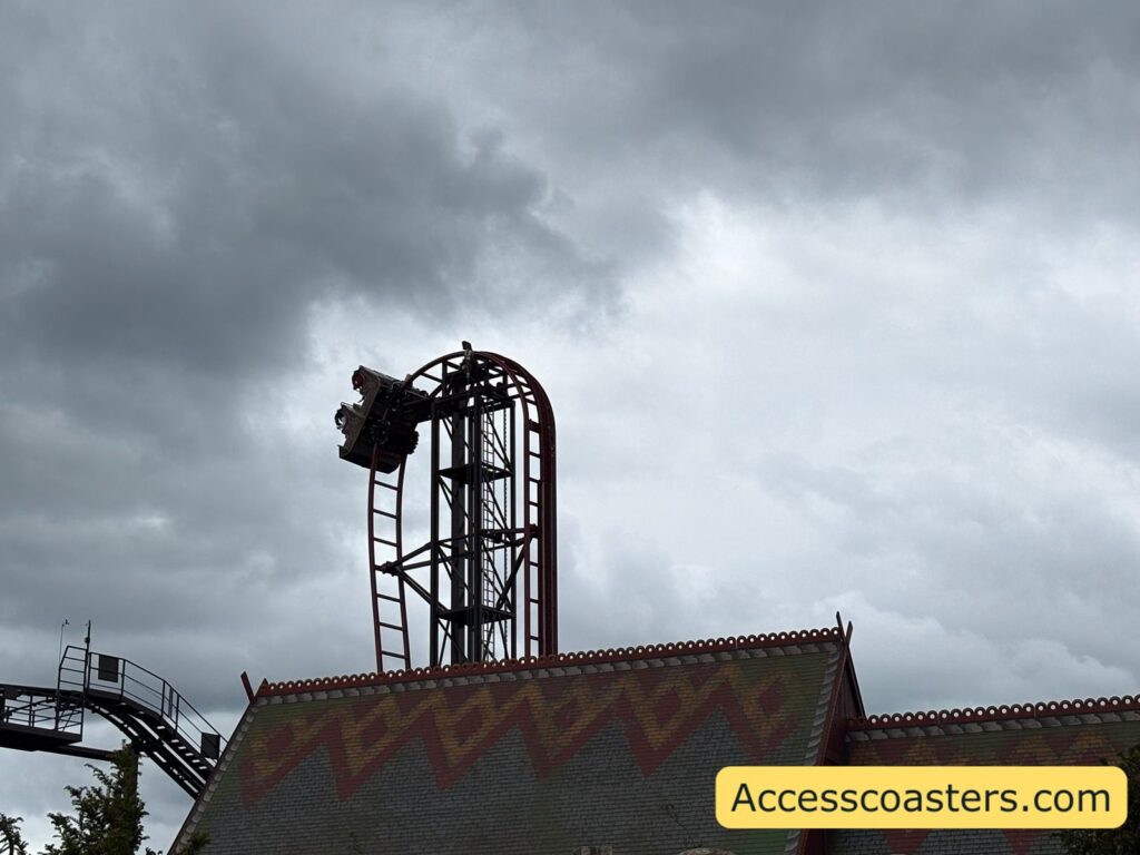image of a Drakon climbing the vertical lift hill. You can see a roof for a building in front of the lift hill. 