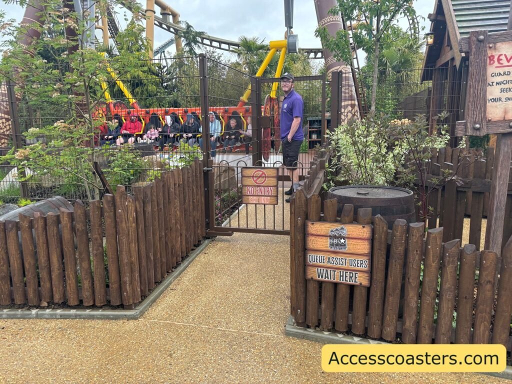 image of ride exit gate and queue assist entrance with sign that reads queue assist users wait here. in the background you can see Vild swing ride being loaded with people. 