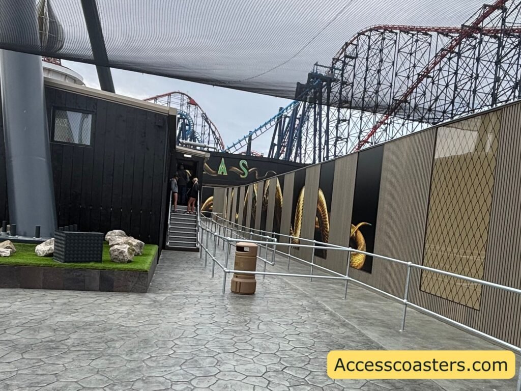 indoor queue line building with stairs leading up for the easy access entrance there is grey queue line railings to the right for the main queue